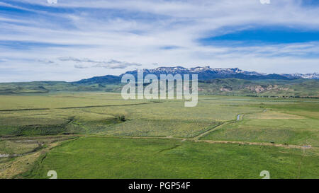 Les champs verts jeter au-dessous d'une chaîne de montagnes couvertes de neige dans l'ouest des États-Unis d'Amérique. Banque D'Images