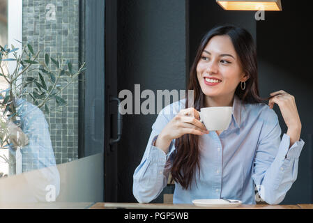 Jolie femme regarde par la fenêtre de boire du café Banque D'Images