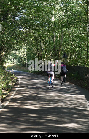 Vu de l'arrière 2 hommes sur push up vélo Vélos une colline escarpée lane près de Bradfield, Sheffield, Yorkshire, Angleterre Banque D'Images