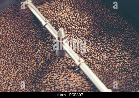 Les grains de café fraîchement torréfié provenant d'un grand torréfacteur de café est versé dans le cylindre de refroidissement. Motion Blur sur les haricots. Banque D'Images