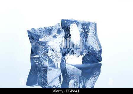 Deux des cubes de glace avec fusion waterdrops sur fond blanc réfléchissant Banque D'Images