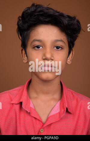 Jeune Indien boy wearing smart casual clothing contre bac brun Banque D'Images