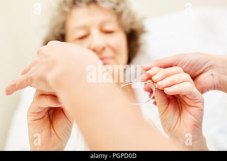 Le fournisseur de soins principal donne femme lunettes de lecture en sciences infirmières Banque D'Images