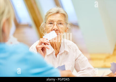 Senior woman with dementia joue aux cartes avec la pression dans la maison de soins infirmiers ou à la maison Banque D'Images