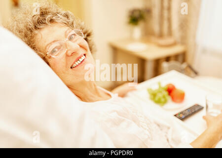 Happy senior woman est au lit dans sa maison pour personnes âgées ou maison de retraite Banque D'Images