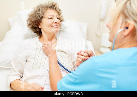 Avec la respiration contrôle infirmière stéthoscope dans a senior patient Banque D'Images