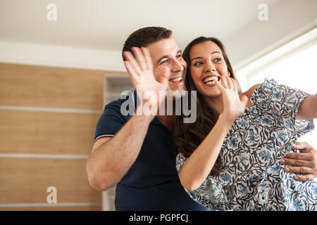 Belle femme et mari appelant leur parent pour leur montrer la nouvelle télévision qu'ils ont obtenu. Heureux couple forme à l'appareil photo Banque D'Images