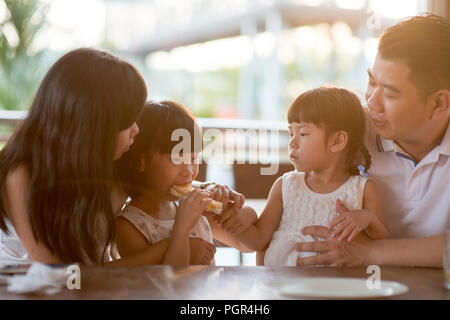 L'alimentation des enfants et le partage du pain pour le cafétéria. Vie de plein air famille asiatique avec lumière naturelle. Banque D'Images