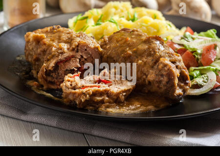 Rouleaux de porc en sauce servi avec une purée de pommes de terre et salade Banque D'Images