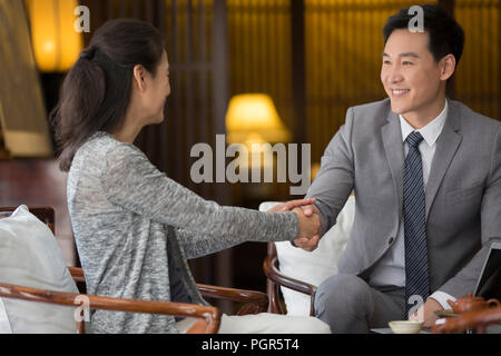 Confident financial consultant shaking hands with mature woman Banque D'Images