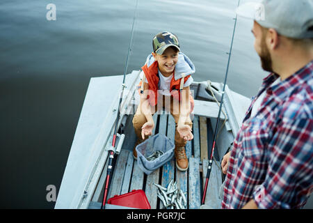 Heureux fils montrant prises à son père alors qu'ils sont dans le bateau Banque D'Images