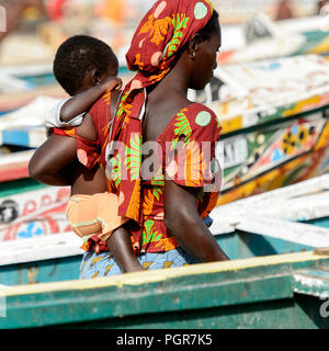 KAYAR, SÉNÉGAL - AVR 27, 2017 : femme sénégalaise non identifié porte un bébé sur la côte de l'océan Atlantique. De nombreuses personnes travaillent au port de Kayar Banque D'Images