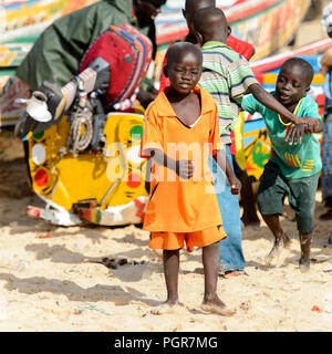 KAYAR, SÉNÉGAL - AVR 27, 2017 : petit garçon sénégalais non identifiés en costume orange promenades sur la côte de l'océan Atlantique. De nombreuses personnes travaillent dans Kayar p Banque D'Images