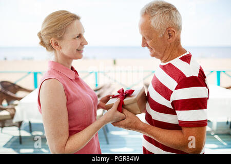 De l'homme tenant la main de sa femme en passant son paquet cadeau avec Banque D'Images