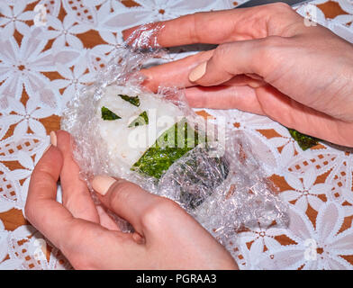 Woman's mains cuisine onigiri maison originale avec un visage souriant fait de nori Banque D'Images