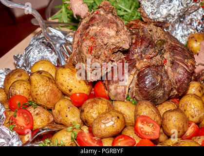 Grande paix de la viande de mouton bien moyen rôti avec pommes de terre au four et tomates fraîches Banque D'Images