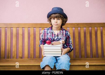 Little Boy holding pile de livres prêt à retourner à l'école. Banque D'Images