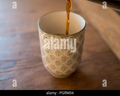 Verser le café chaud fait maison dans un mug ou une tasse à la table en bois. Focus sélectif. Banque D'Images