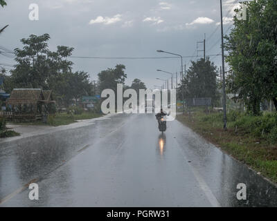 Khao Lak, Thaïlande - 9 janvier 2018 : Fortes pluies sur une route en Thaïlande. Entrée d'asphalte glissante. Moto ou cyclomoteur en premier plan. Banque D'Images