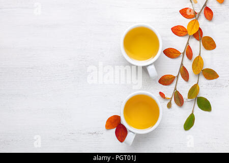 Deux tasses de thé et de feuilles aux couleurs automnales sur table rustique. Banque D'Images