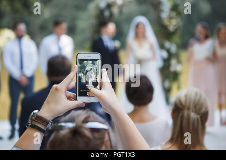 Invité à la cérémonie de mariage prend des photos sur le téléphone de l'Jeunes mariés Banque D'Images