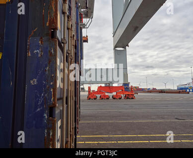 Les bogies à roues rouge et patte d'un grand conteneur grue, à côté d'un conteneur bleu à Alaskahaven La borne à Amsterdam, Hollande. Banque D'Images