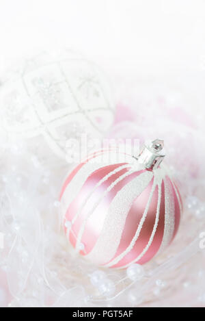 Belle décoration de Noël en blanc et rose Couleurs : plusieurs des boules de Noël avec ruban blanc et perles sur un fond clair, avec espace pour te Banque D'Images