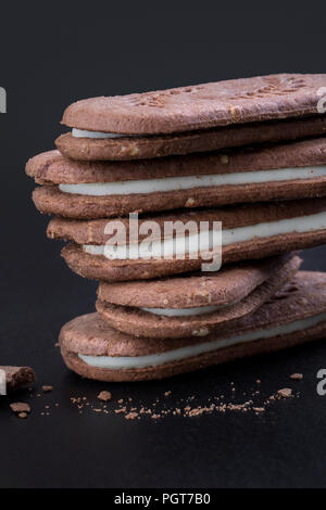 Sandwich cookies au chocolat avec crème blanche sur fond noir, close-up side view Banque D'Images