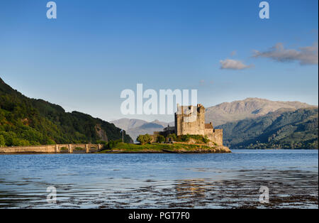 Restauré le château d'Eilean Donan sur l'île d'Eilean Donan avec arche la passerelle au coucher du soleil avec les montagnes de Glenelg Highlands écossais Ecosse Banque D'Images