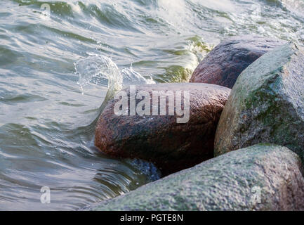 Quatre grosses pierres de granit situé près de l'eau, l'eau sous la forme d'une vague distincte est brisée contre les pierres, un léger coup de feu, l'eau Banque D'Images