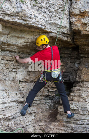 Photo de l'arrière de l'escalade sports guy en casque jaune sur la roche Banque D'Images