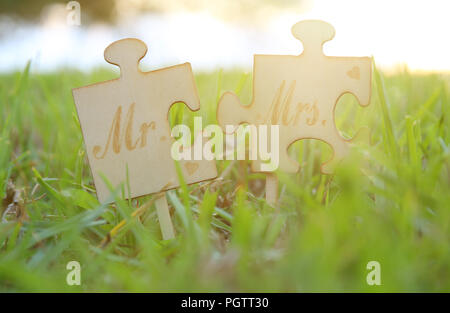 M. et Mme signe. Deux pièces du puzzle placés dans l'herbe pendant l'heure du coucher du soleil et l'harmonie. concept de mariage Banque D'Images