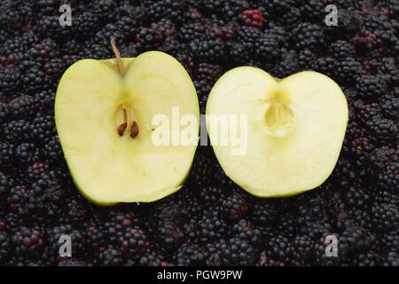 Deux moitiés de pomme sur un lit de mûres Banque D'Images