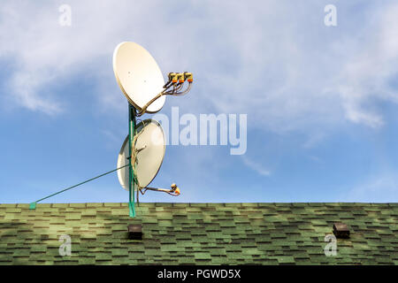 Antenne Satellite Antennes sur toit d''une maison couverte de tuiles bardeaux. Ciel bleu sur journée ensoleillée sur l'arrière-plan. Copyspace. Banque D'Images