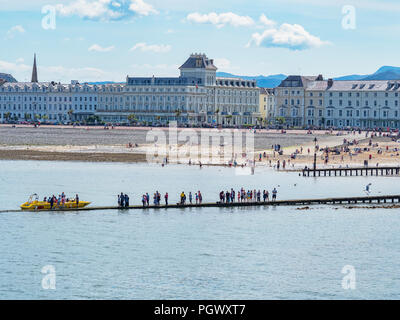 25 Juillet 2018 : Llandudno, Conwy, UK - une ligne de personnes en attente pour des excursions en bateau sur la promenade de Llandudno beach sur une chaude journée de juillet pendant l'heatwav Banque D'Images