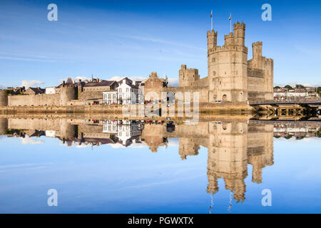 Un soir d'été au château de Caernarfon, Gwynedd, au nord du Pays de Galles. Le château se reflète dans la rivière Banque D'Images