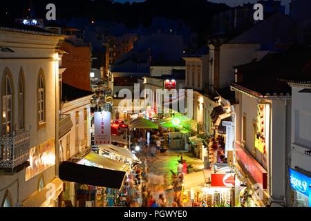 Portrait de la R 5 de Outubro shopping street dans la soirée avec les touristes appréciant les paramètre, Albufeira, Portugal, Europe. Banque D'Images