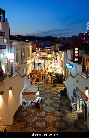 Portrait de la R 5 de Outubro shopping street dans la soirée avec les touristes appréciant les paramètre, Albufeira, Portugal, Europe. Banque D'Images