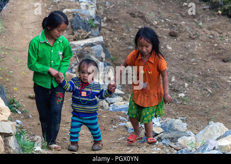Ha Giang, Vietnam - Mars 17, 2018 : les enfants de minorités ethniques Hmong de marcher sur une route pavée dans un village dans les montagnes du nord du Vietnam Banque D'Images
