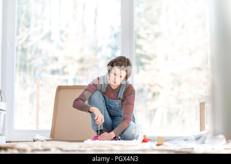 Jeune femme faisant des réparations bricolage à la maison mettre ensemble mobilier d'auto assemblage à l'aide d'un tournevis. Banque D'Images