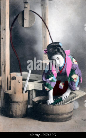 [ 1910 - Japon femme japonaise en Kimono Lessive ] - Un studio photo d'une jeune japonaise en kimono traditionnel et se faisant passer pour une femme au foyer coiffure faire le lavage avec un bordage et un seau en bois (oke). 20e siècle vintage carte postale. Banque D'Images