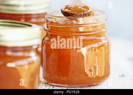 Cuillère en bois plein de confiture de cantaloup faits maison se reposant dans un pot ouvert rempli de confiture. Selective focus on pot Mason dans le centre. Banque D'Images