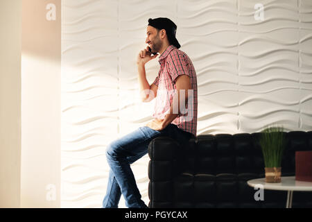 Jeune Latino Man Talking On Cell Phone At Home Banque D'Images