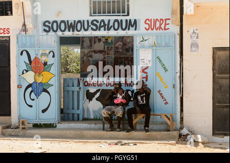 Route de LAMPOUL, SÉNÉGAL - Apr 23, 2017 : deux hommes sénégalais non identifiés et une petite fille s'asseoir près de la boutique. Encore beaucoup de personnes au Sénégal vivent dans pover Banque D'Images