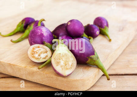 Groupe d'aubergines bébé violet sur planche à découper en bois. Banque D'Images