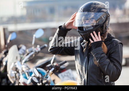 Motocycliste Caucasian woman pose son casque intégral, contre l'arrière-plan, portrait de vélos copyspace Banque D'Images