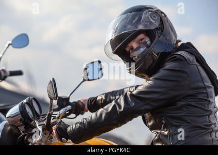 Pilote moto en noir est titulaire d'volant et looking at camera, Caucasian woman Banque D'Images