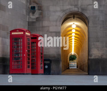 Manchester, Angleterre, RU - 1 juillet 2018 : Deux boîtes de téléphone rouge traditionnel debout à côté d'un couloir éclairé d'Arches dans l'hôtel de ville de Manchester Exten Banque D'Images