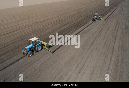 Deux tracteur bleu vif de labourer le sol contre un arrière-plan de la terre noire. Banque D'Images