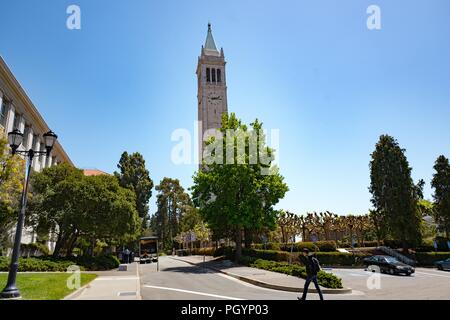 Un jeune étudiant marche dernières Sather Tower (aka le campanile) et d'autres bâtiments du campus sur une journée ensoleillée sur le campus principal de l'université de Berkeley dans le centre-ville de Berkeley, Californie, le 21 mai 2018. () Banque D'Images